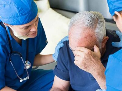 Nurses examining an ill senior patient during a home visit.